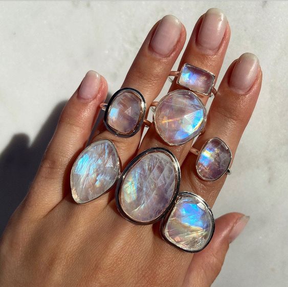 Moonstone jewelry is depicted on the model's hand. The meaning of moonstone crystal varies across cultures, but some common themes are creativity, protection, and healing. 