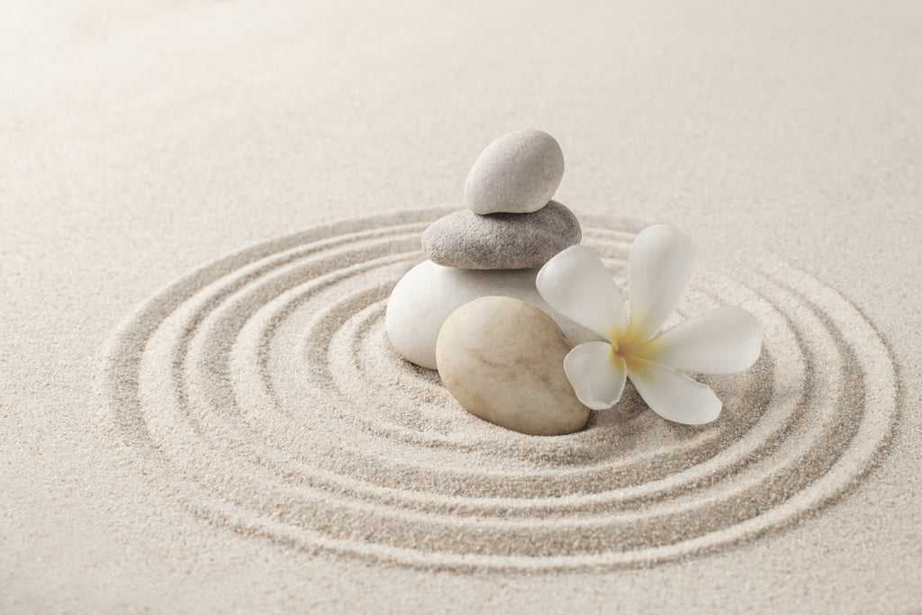 Stacked zen stones against a sand background promoting inner peace and wellness.