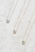 Three evil eye mother of pearl necklaces in gold, silver, and rosegold finish.