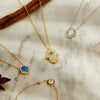 Several Opalite necklaces and evil eye bracelets are displayed against a marble background.