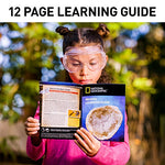 A young girl wearing safety glasses is reading the Geodes Learning Guide book written by National Geographic.