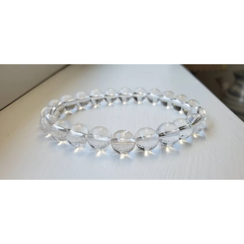 8mm Clear Quartz Gemstone Bracelet on a counter with a close up of the beads.